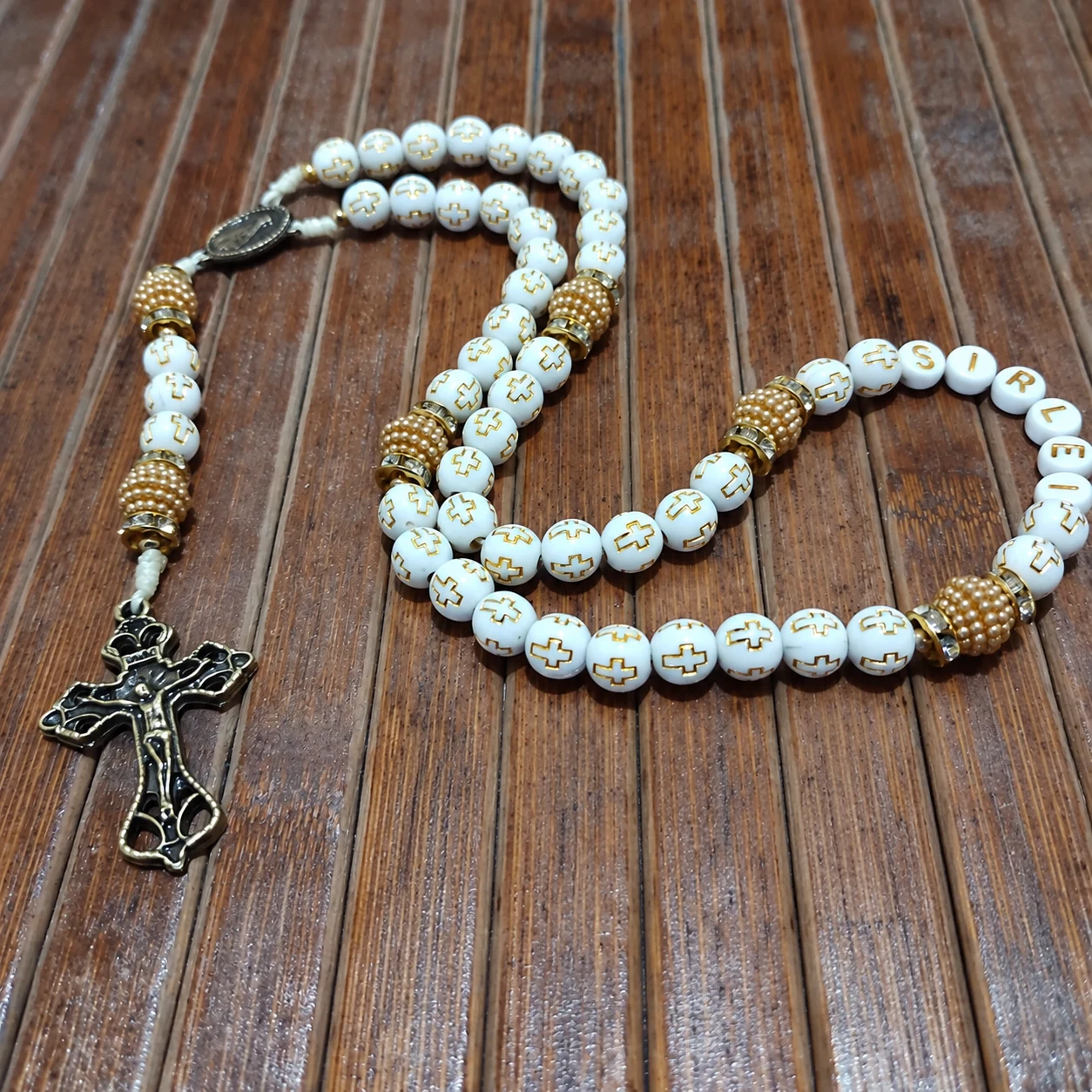 Terço branco com nome e detalhes dourados, peça feita pela Artes da Val